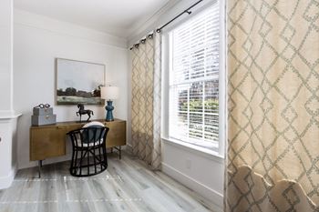 a home office with a desk and a large window